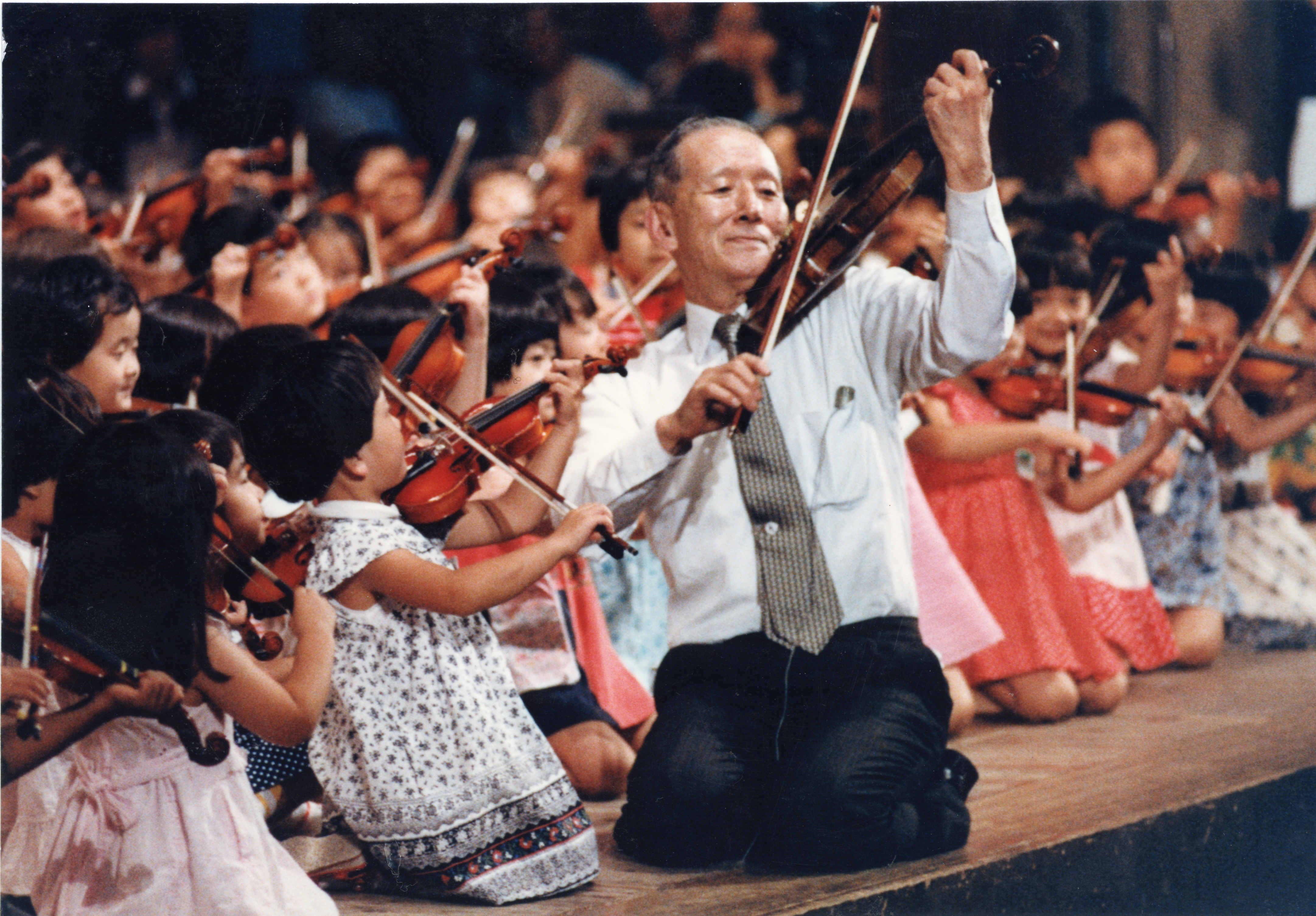 Dr. Suzuki playing violin in a group of children